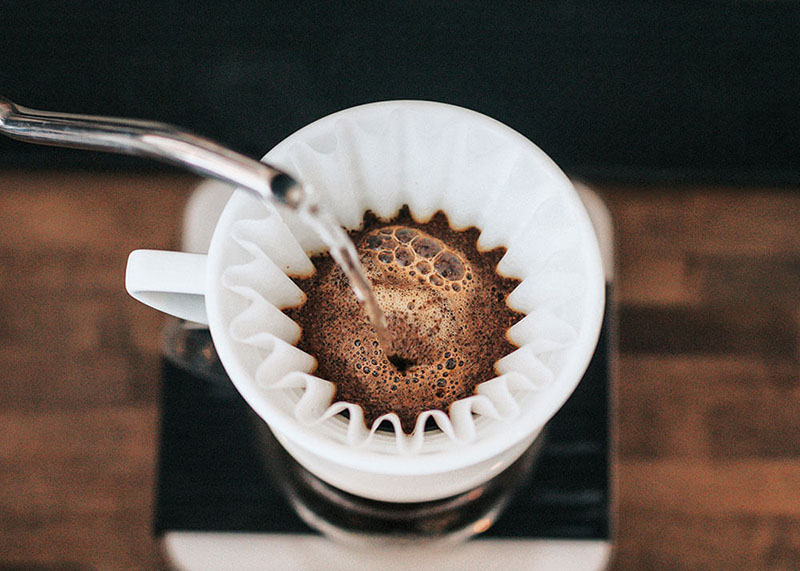 Hot water poured from metal flask into drip coffee