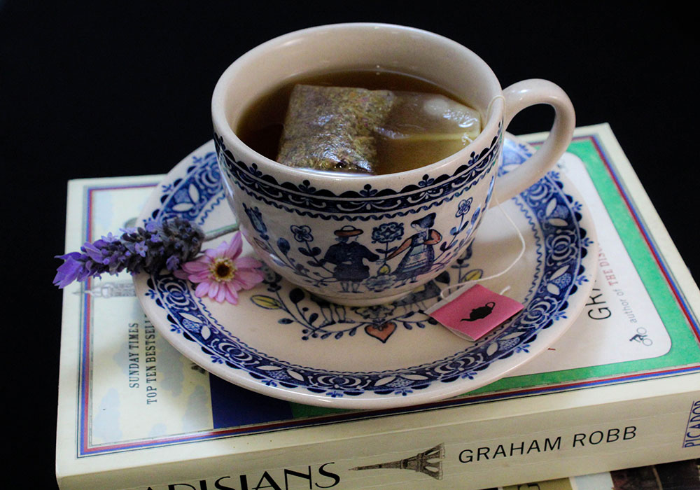 Tea bag steeped in cup and saucer on top of a few books