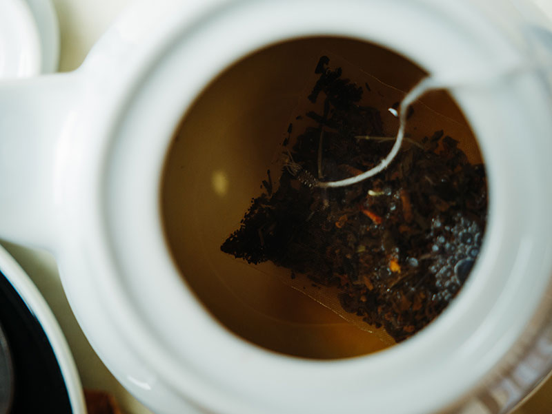 Steeping a tea bag in a pot of hot water