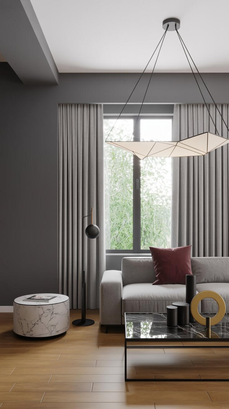 Modern living room with gray sofa, geometric light fixture, marble side table, and floor lamp. Large window with curtains and greenery outside.