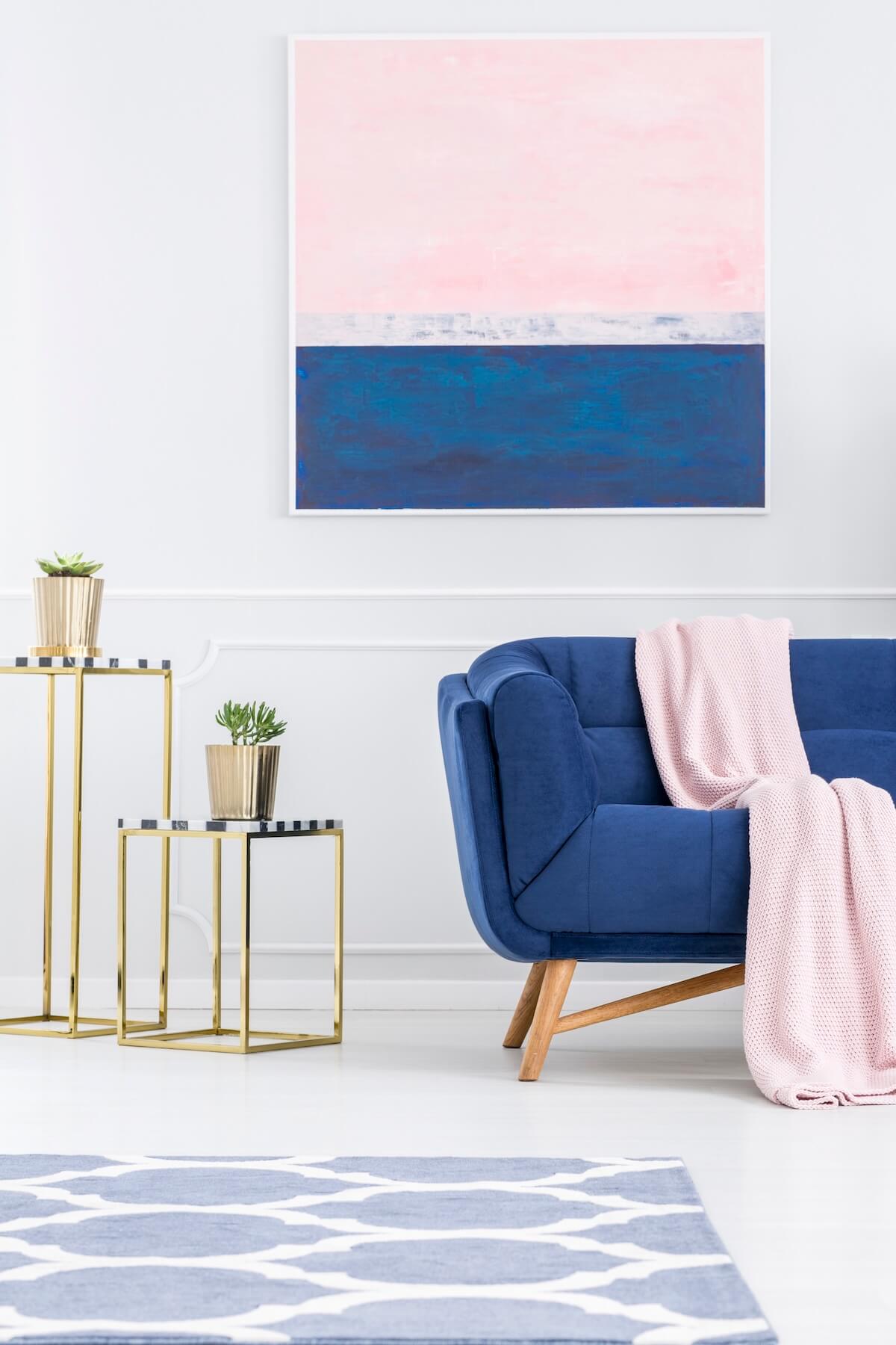 Living room with blue velvet sofa pink accents abstract art