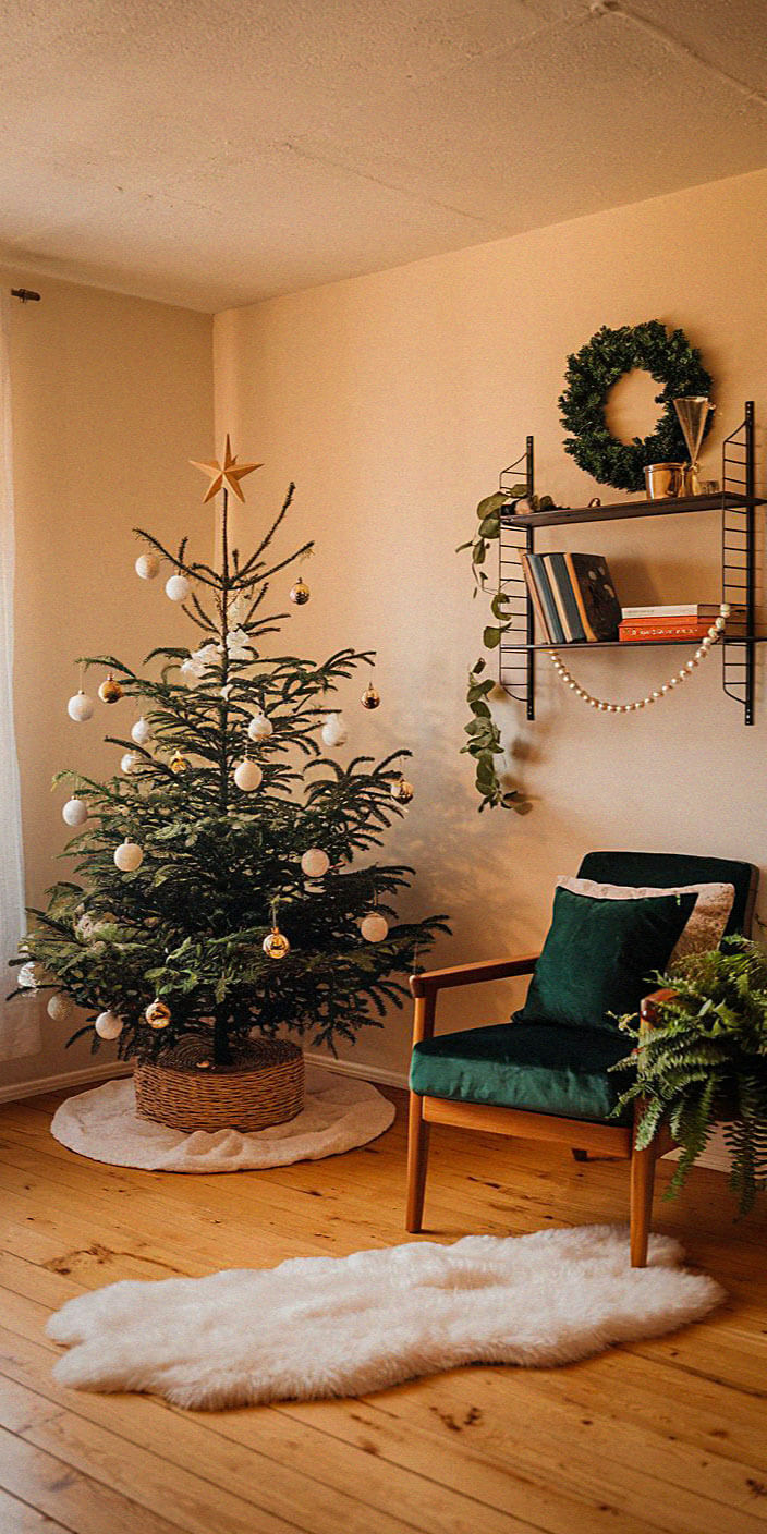 A cozy room with a decorated Christmas tree, green chair, bookshelves, and a wreath, creating a warm, festive atmosphere.
