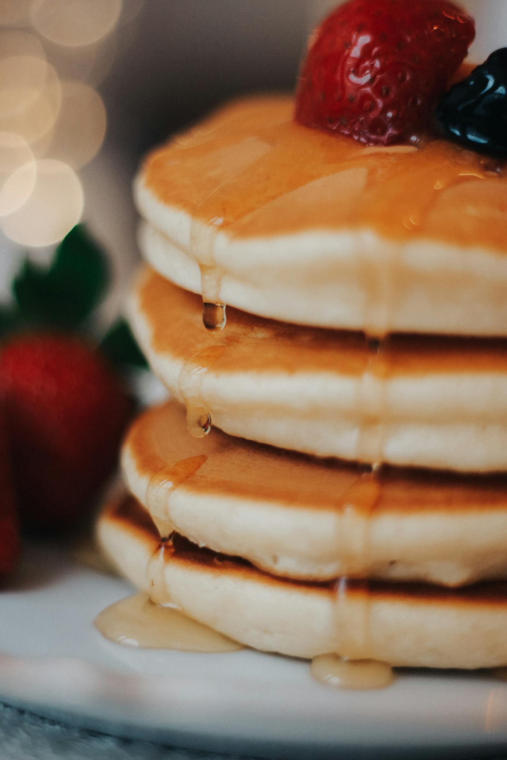 Close-up of a delicious pancake stack with berries and honey, perfect for breakfast lovers.