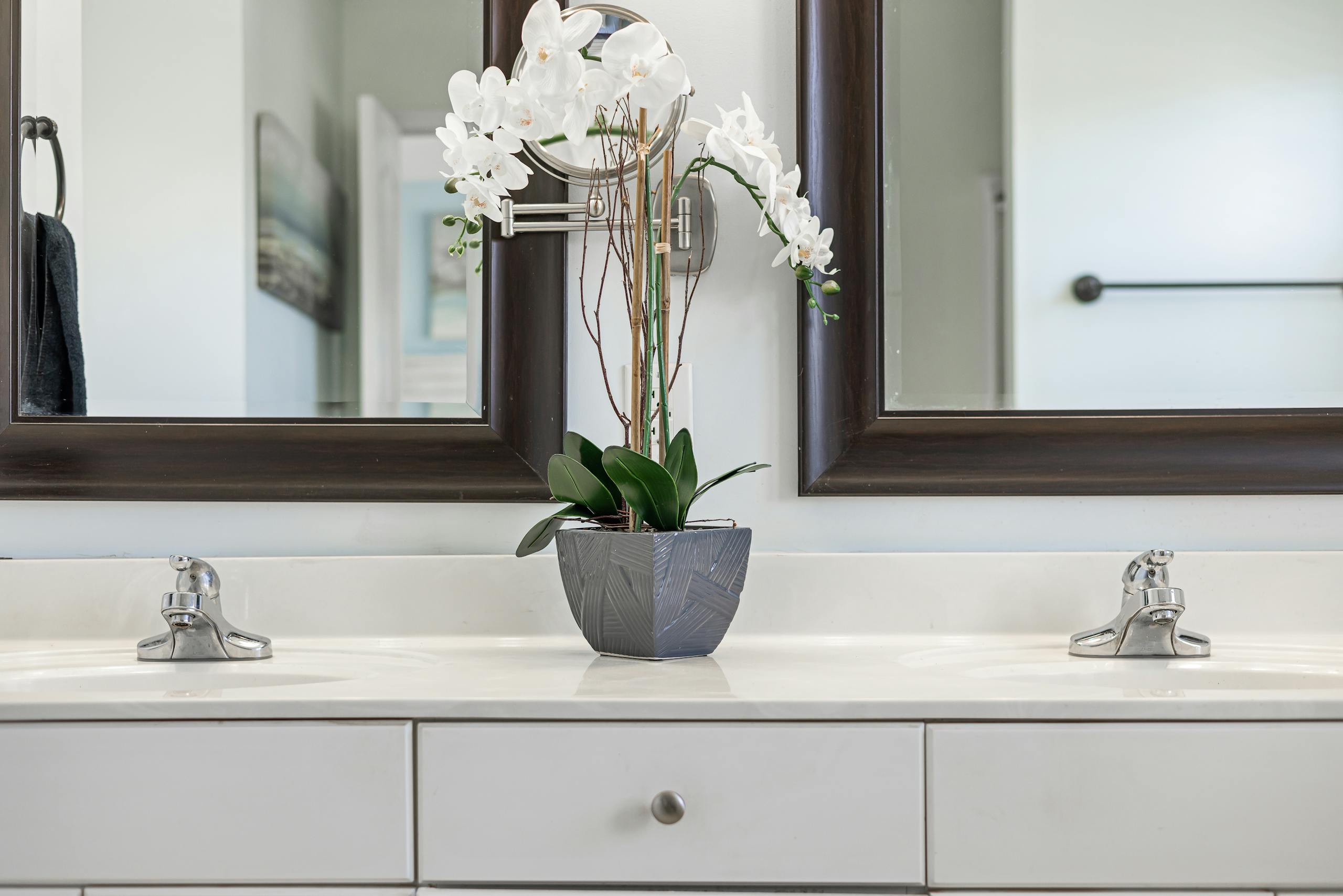 Contemporary bathroom with double sink, mirror, and elegant orchid centerpiece for a minimalist touch.
