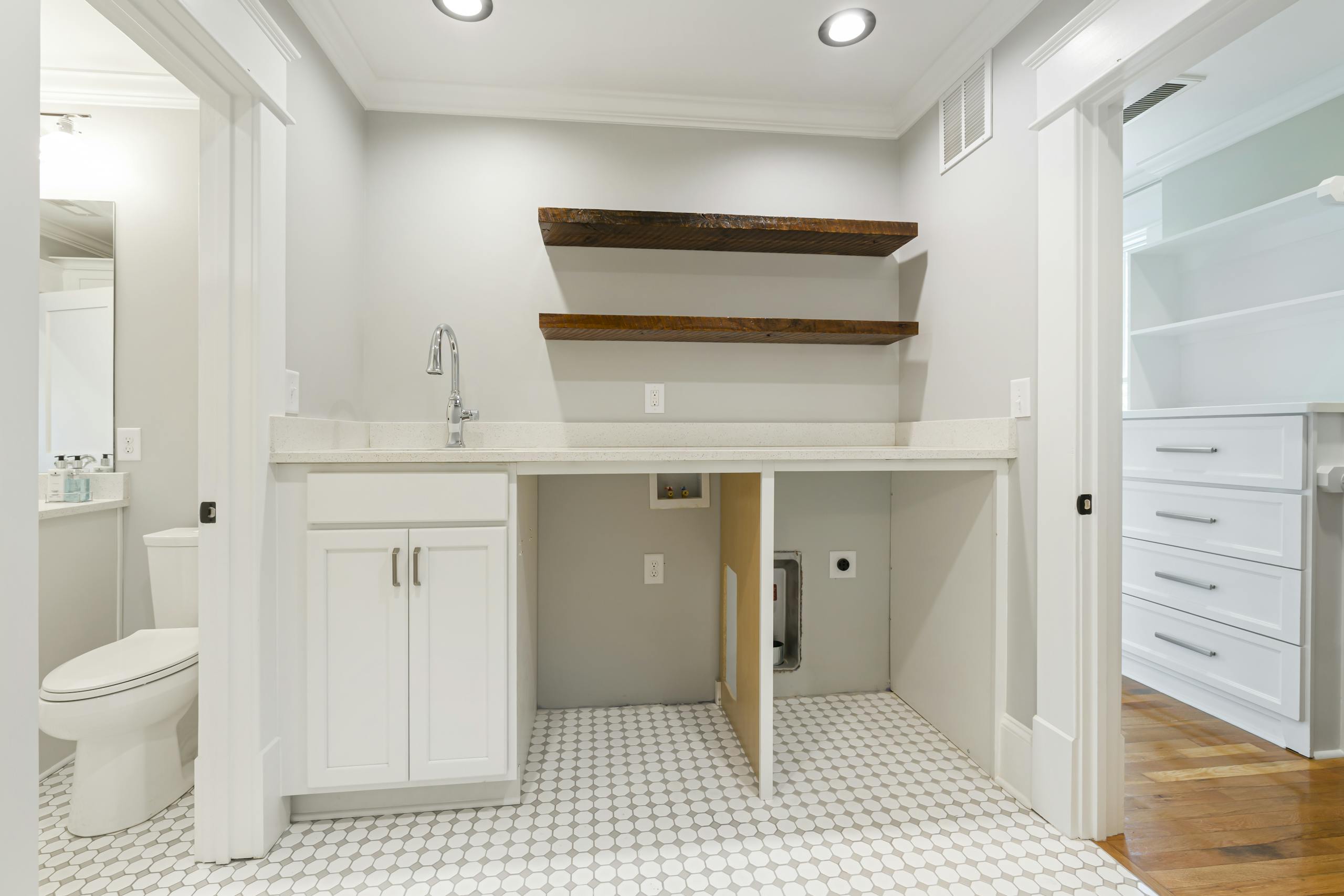 Spacious bathroom interior with white cabinets and wooden shelves, offering ample storage.