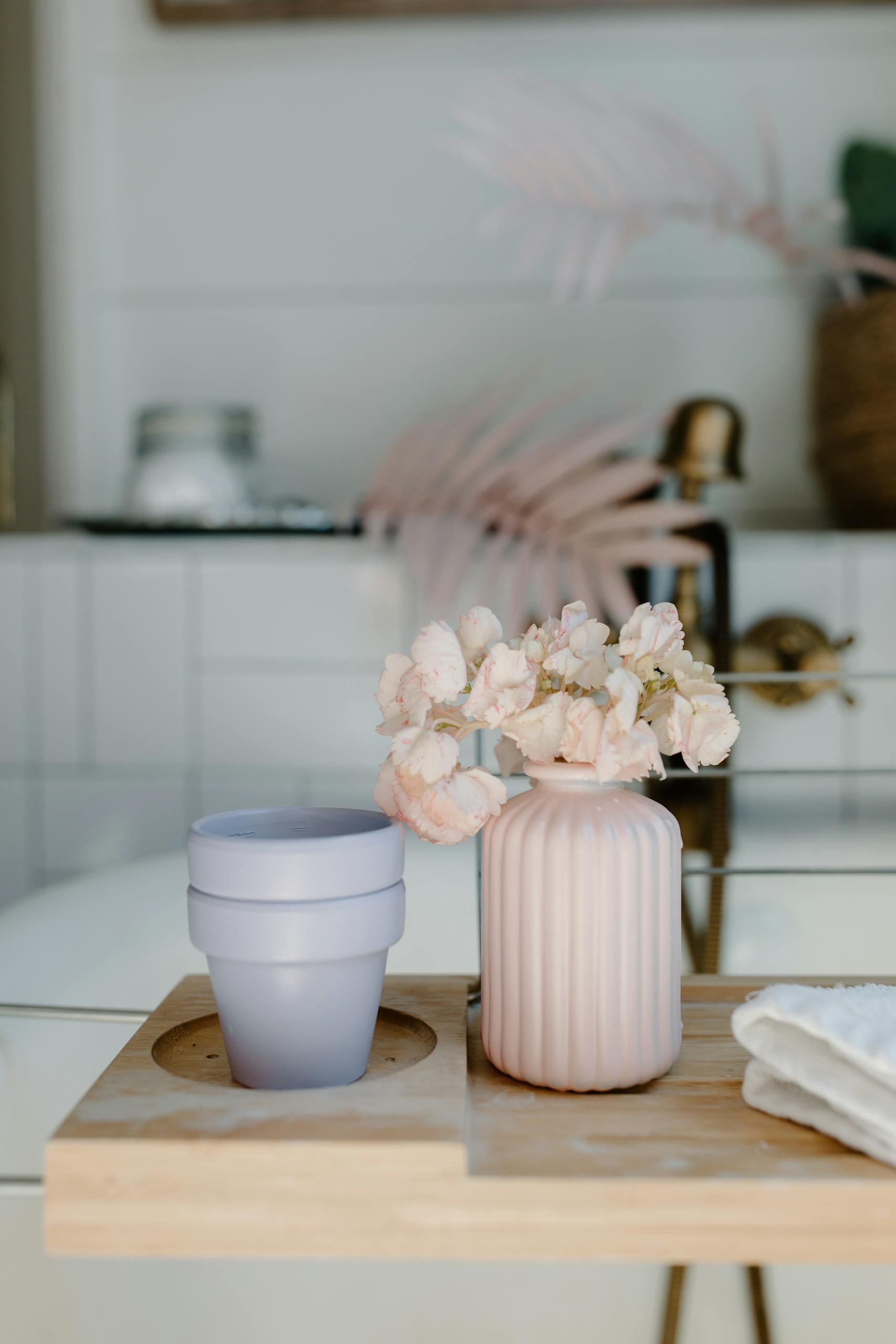 Stylish bathroom setup featuring pink flowers in a vase on a wooden tray.