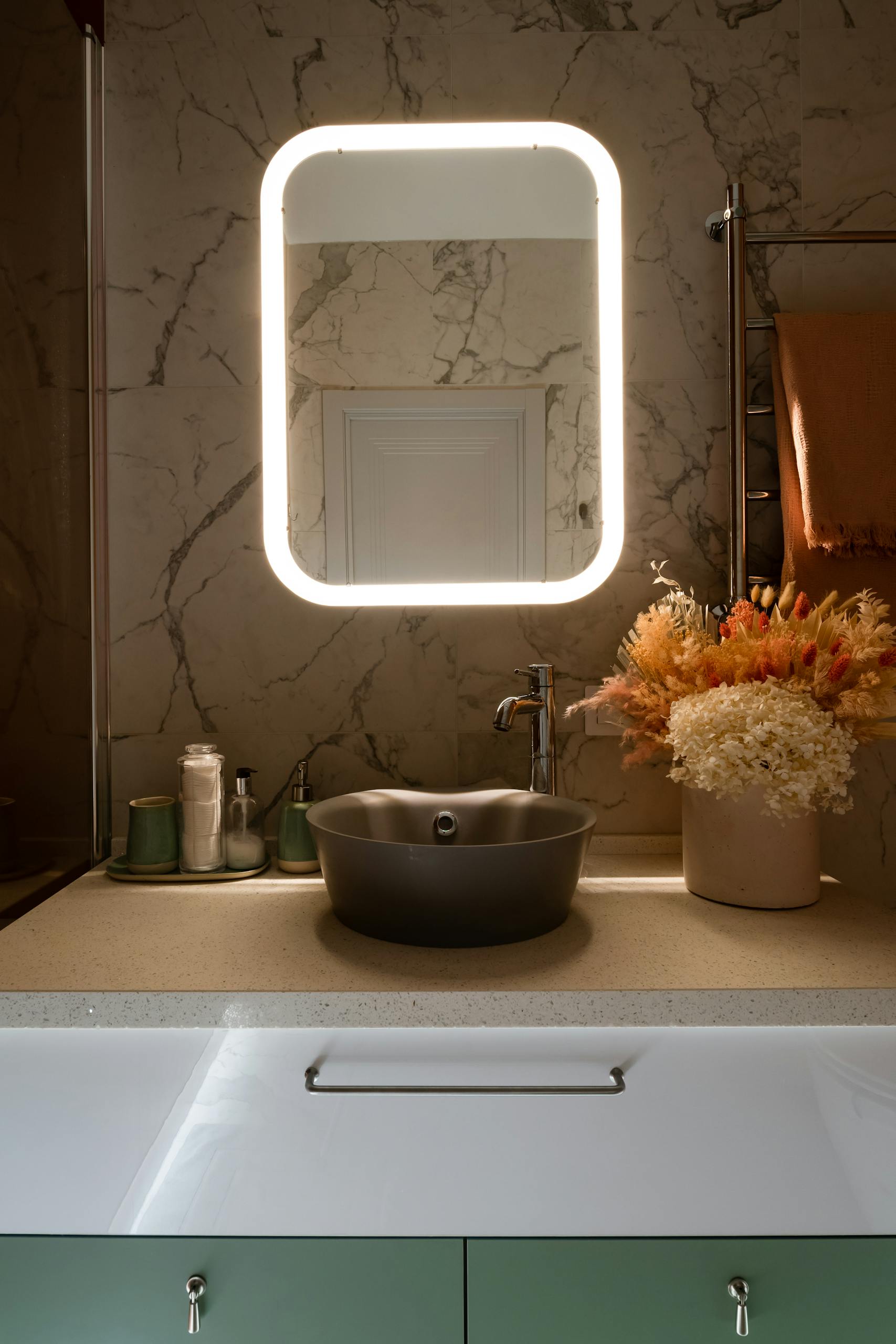 Stylish bathroom with illuminated mirror, marble wall, and modern sink in Saint Petersburg.
