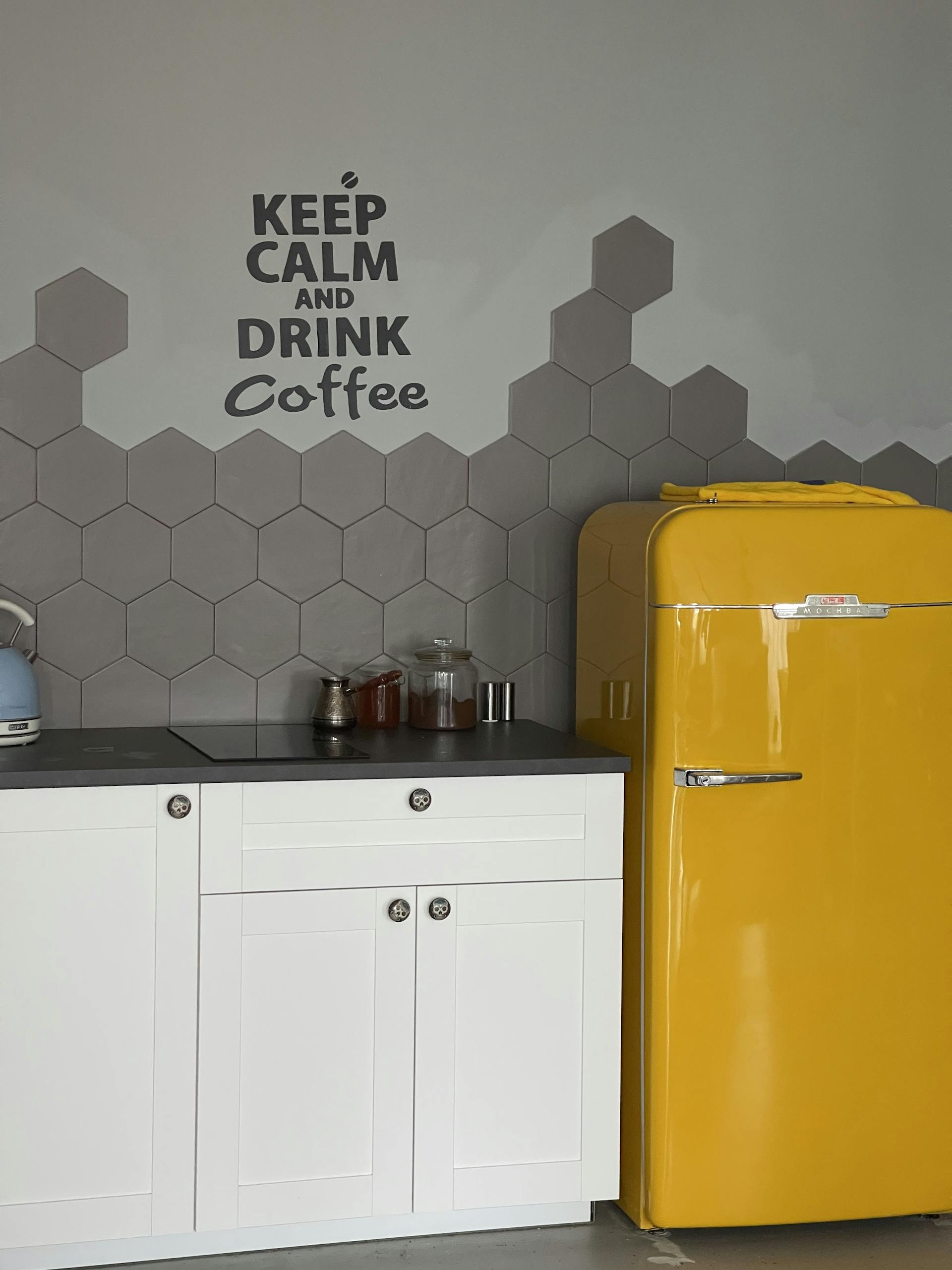 Stylish kitchen featuring a vibrant yellow fridge and coffee-themed decor.