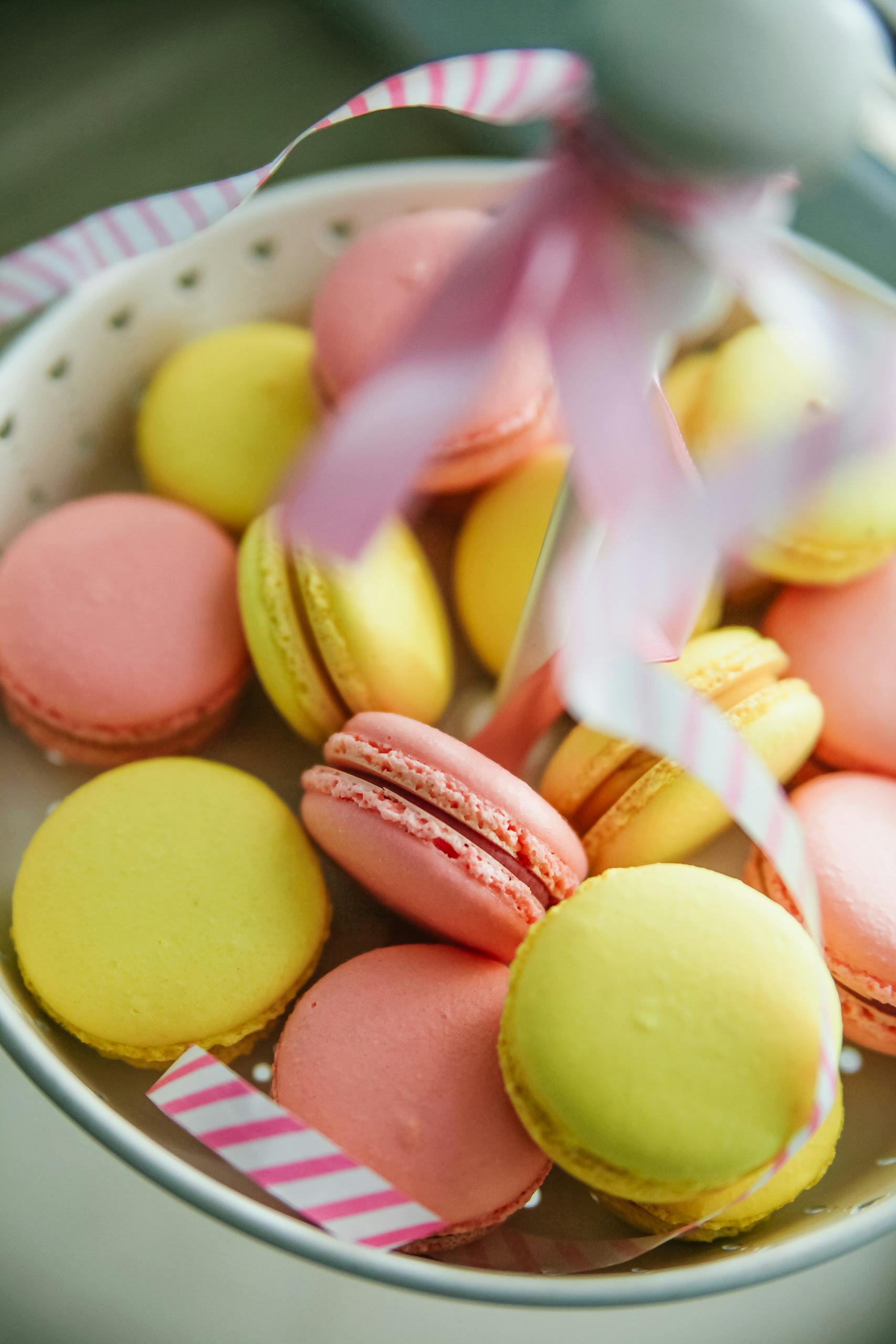 A vibrant display of pink and yellow macarons on a ceramic plate, perfect for dessert ideas.